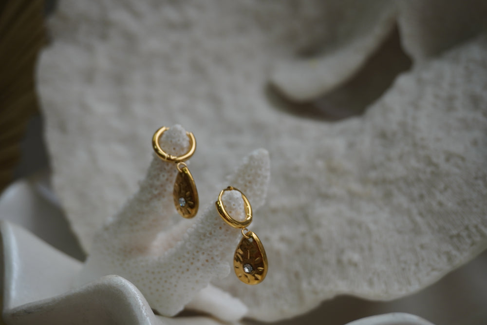 Alternate view: gold-tone hoop earrings with teardrop charms, round clear accents and sunburst markings.
