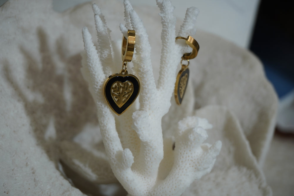 Alternate view: gold-tone hoop earrings with black-bordered heart drops and open tree-and-leaf centres.