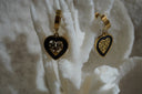 Gold-tone hoop earrings with black-bordered heart drops and open tree-and-leaf centres.