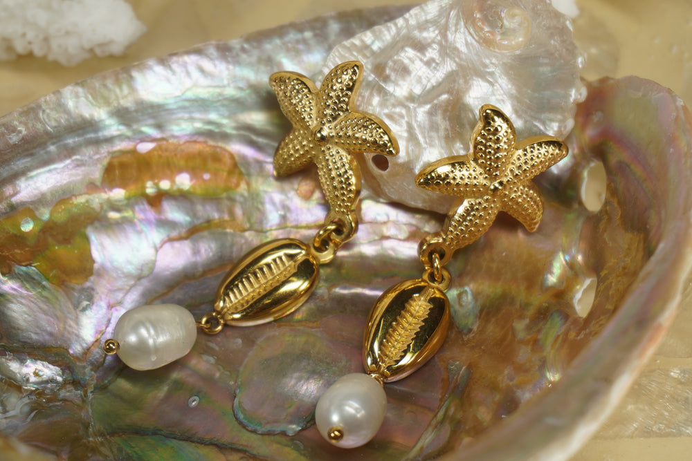 Gold-tone drop earrings with dotted starfish tops, cowrie motifs and white bead drops.