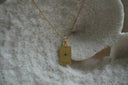 Gold-tone necklace with a rectangular The World pendant, orbital circles, small dots and XXI lettering.