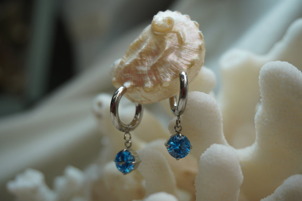 Alternate view: silver-tone hoop earrings with hanging faceted round blue accents.