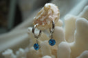 Alternate view: silver-tone hoop earrings with hanging faceted round blue accents.