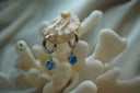 Silver-tone hoop earrings with hanging faceted round blue accents.