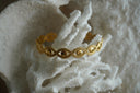 Alternate view: gold-tone open cuff formed from repeated eye shapes with round centres and dotted borders.