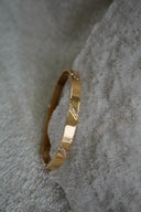 Alternate view: gold-tone bangle with diagonal rows of clear accents across a smooth band.