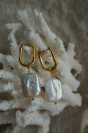 Elongated gold-tone hoops with pale iridescent rectangular bead drops.