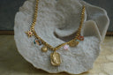 Gold-tone necklace with sun, star, crescent and flower charms surrounding a textured moon-face plaque.