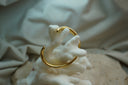 Gold-tone open cuff with a smooth rounded profile and tapered ends.