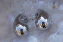 Silver-tone teardrop stud earrings with rounded bases, curved tips and visible posts.