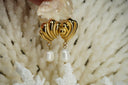 Alternate view: gold-tone sculpted stud earrings with curving raised ridges and white drop-shaped beads.