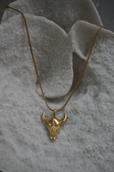 Gold-tone necklace with a smooth bull-skull pendant, upward-curving horns and a close-linked chain.