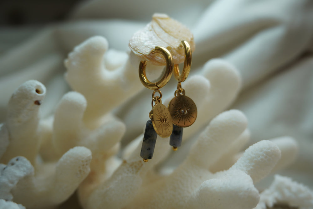 Gold-tone hoops with radiating eye-disc charms and elongated mottled grey beads.