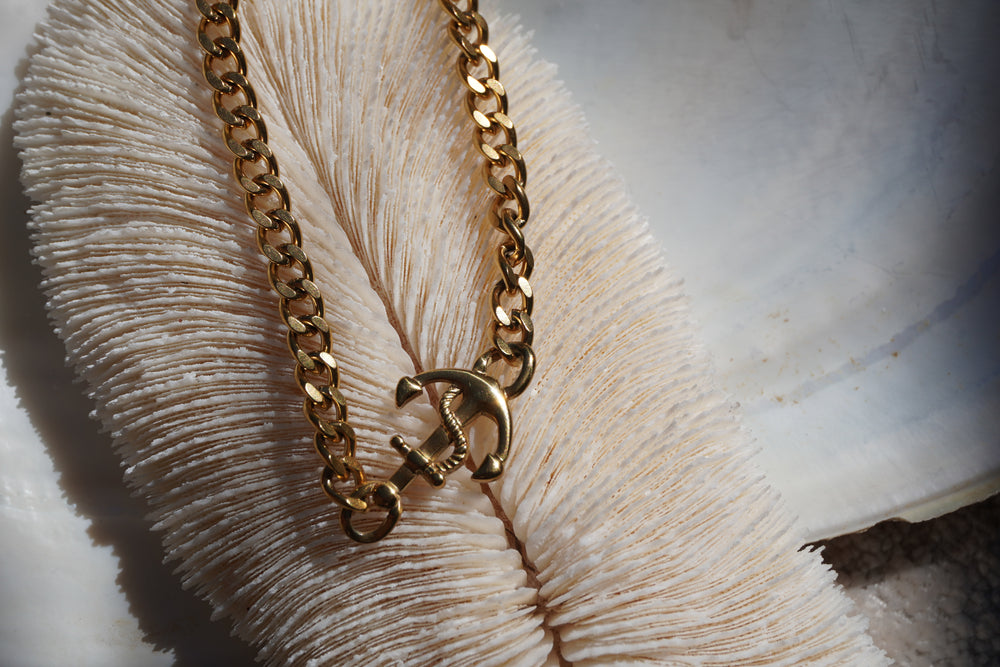 Gold-tone chain bracelet with an anchor centrepiece and twisted rope detail.