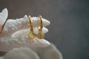 Gold-tone hoop earrings with hanging scallop-shell charms and radiating ridges.