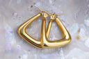 Gold-tone rounded triangular hoop earrings with smooth reflective surfaces.