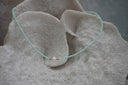Pale-aqua seed-bead necklace with a white centre bead and small gold-tone spacers.
