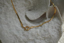 Gold-tone flat-chain necklace with a round centre connector.
