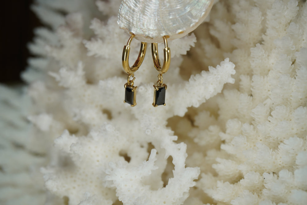 Gold-tone hoop earrings with rectangular black faceted drops in corner-prong frames.