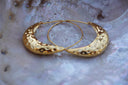 Gold-tone hoop earrings with fine circular wires and broad dimpled crescent-shaped lower sections.
