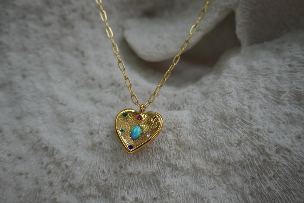 Alternate view: gold-tone heart necklace with a blue-green iridescent oval, coloured accents and elongated chain links.