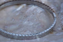 Silver-tone bangle with repeating rectangular ridges around the band.