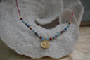Multicoloured beaded necklace with a gold-tone circular medallion and pink centre.