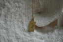 Gold-tone necklace with a rectangular The Lovers pendant, linked-hands illustration and VI lettering.