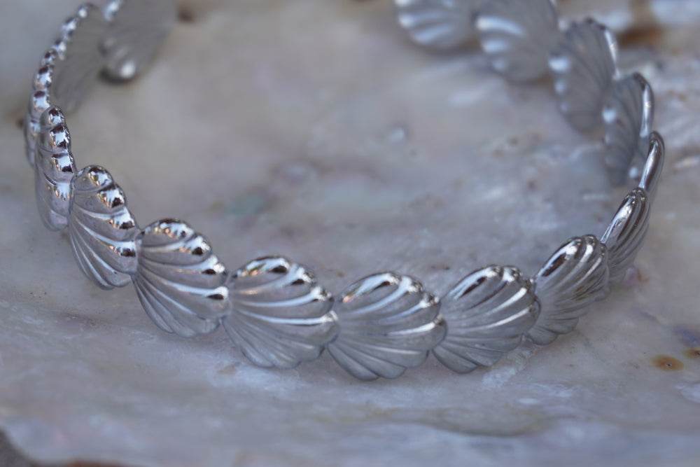 Silver-tone cuff with a repeating row of ridged fan-shell motifs.