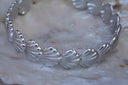 Silver-tone cuff with a repeating row of ridged fan-shell motifs.