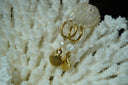 Gold-tone hoop earrings with white rounded beads and hanging ridged scallop-shell charms.