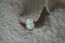 Ring with a gold-tone border and band around an irregular pale iridescent centre.