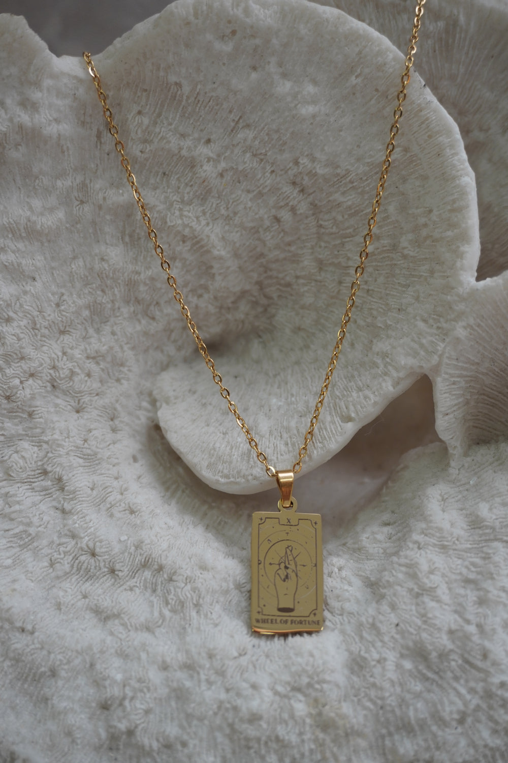 Alternate view: gold-tone necklace with a rectangular Wheel of Fortune pendant showing crossed fingers and X lettering.