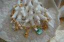 Alternate view: gold-tone link bracelet with starfish, strawberry and fish charms beside an irregular green bead.
