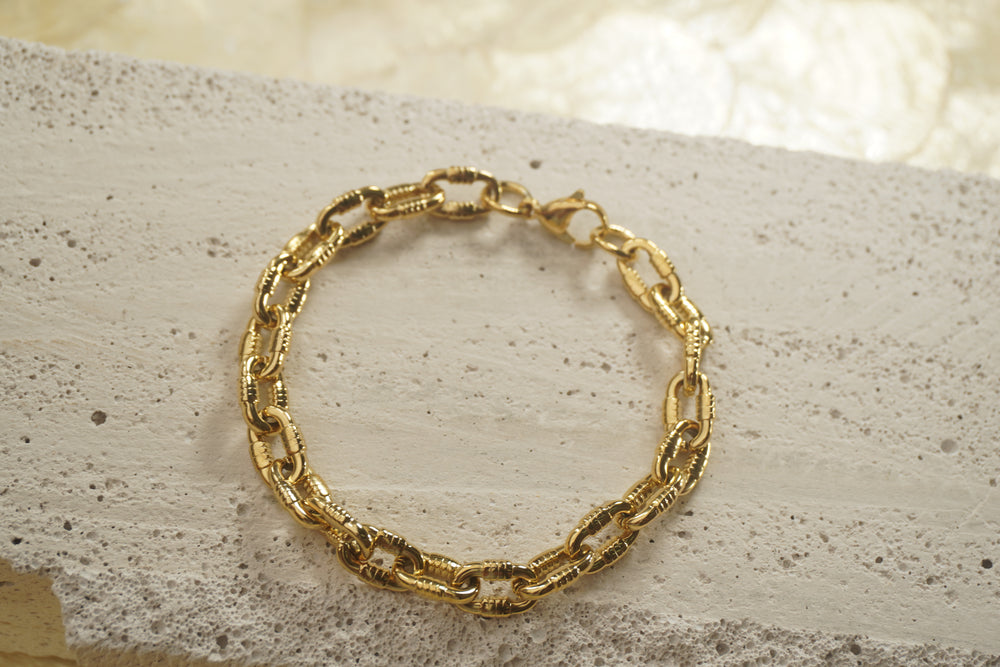 Gold-tone bracelet with thick oval links, ridged side sections and a clasp.
