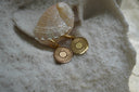 Gold-tone hoop earrings with flat circular disc charms decorated with radiating sunray lines.
