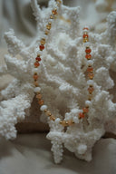 Necklace with orange, peach and white beads separated by gold-tone spacers.