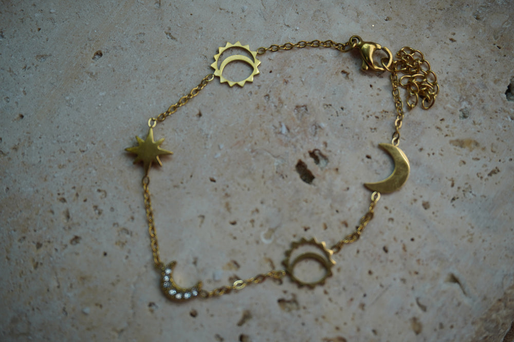 Gold-tone chain bracelet with crescent moons, pointed stars and open sun motifs.