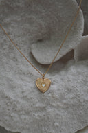 Alternate view: gold-tone necklace with a heart pendant, radiating lines and a small pale heart at the centre.