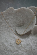 Gold-tone necklace with a heart pendant, radiating lines and a small pale heart at the centre.