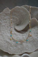 Alternate view: gold-tone necklace with wavy bar links, dangling scallop-shell charms and blue bead drops.