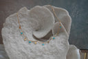 Gold-tone necklace with wavy bar links, dangling scallop-shell charms and blue bead drops.