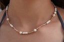 Worn view: necklace with peach and lilac faceted beads, stacked white discs, rounded white beads and gold-tone accents.