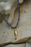 Alternate view: blue round-bead necklace with a textured gold-tone fish pendant and small gold-tone disc charms.