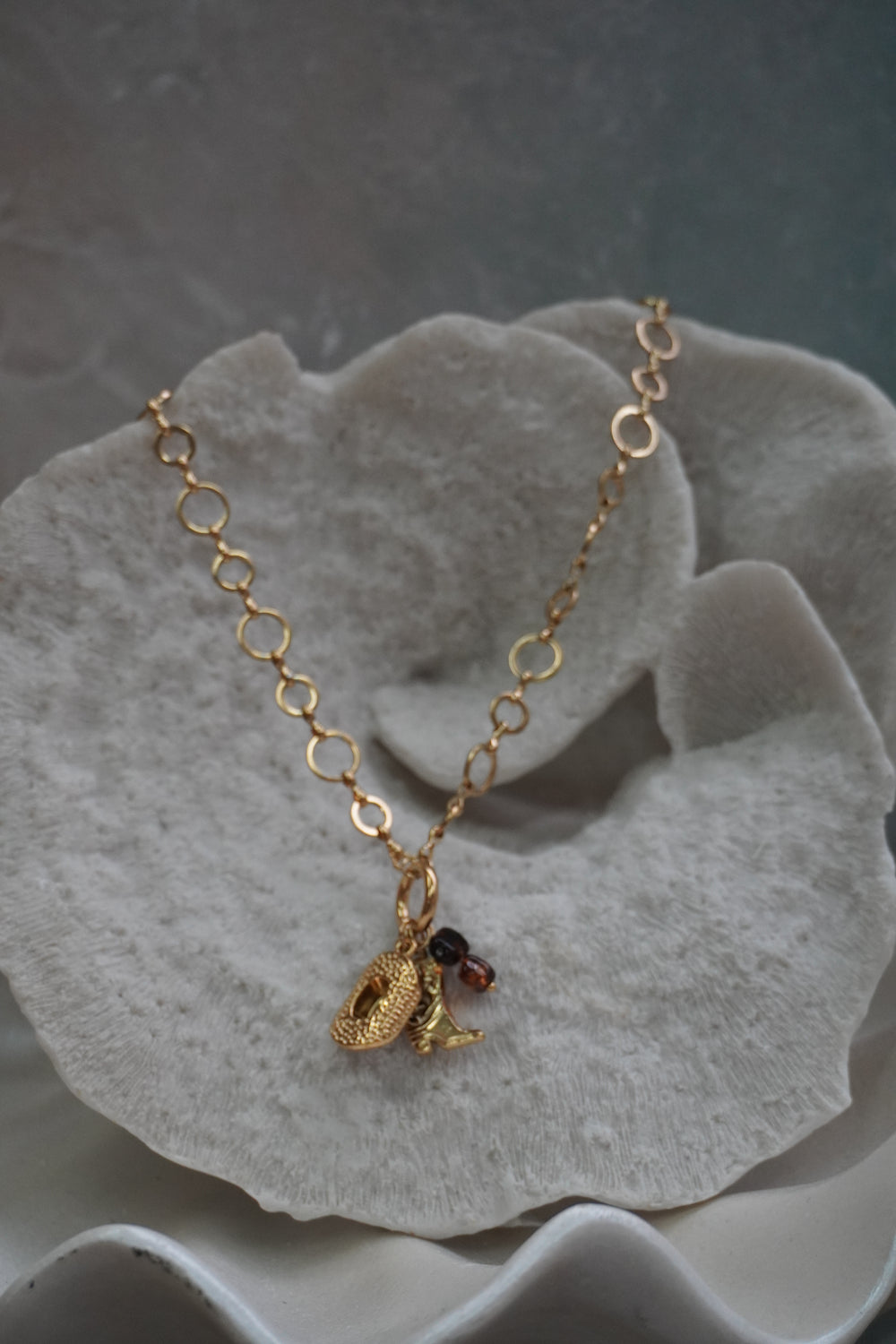 Gold-tone open-link necklace with western hat and boot charms and dark brown beads.
