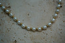 Alternate view: necklace with white oval beads alternating with small gold-tone spheres.