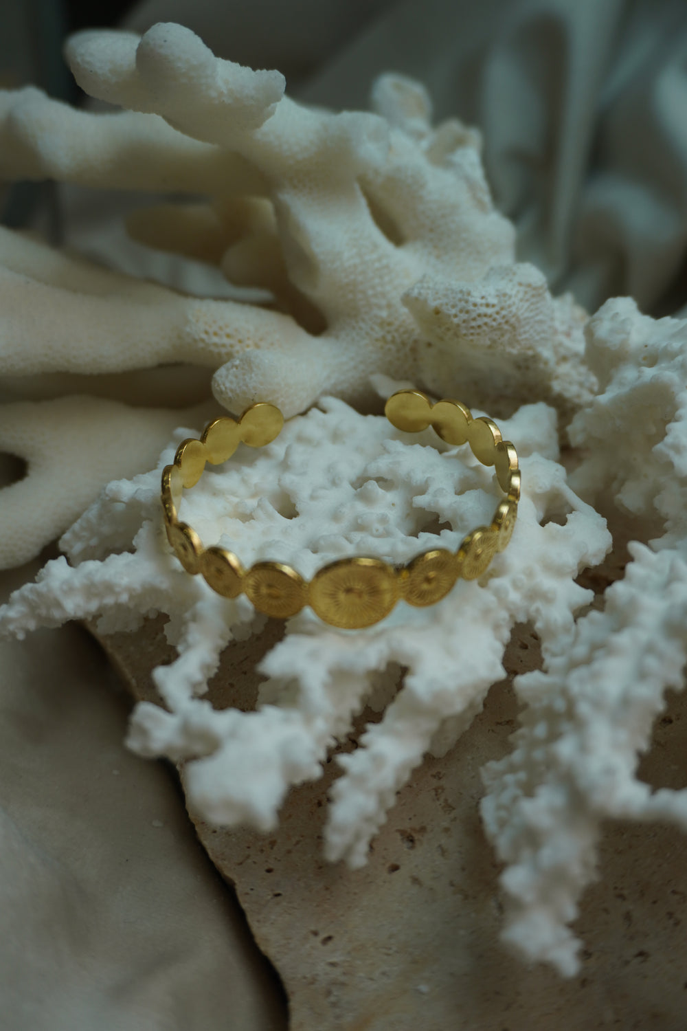 Alternate view: gold-tone open cuff formed from graduated discs with radiating lines and raised centres.
