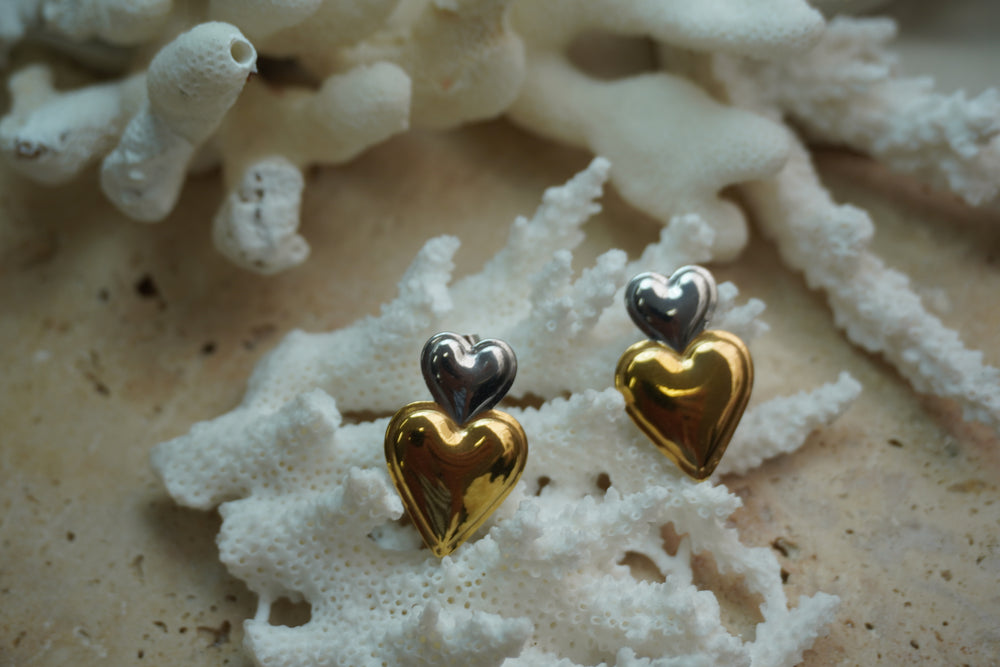 Alternate view: earrings with a small silver-tone heart above a larger reflective gold-tone heart.