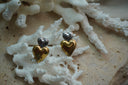 Earrings with a small silver-tone heart above a larger reflective gold-tone heart.