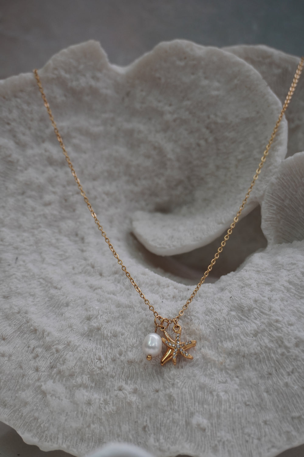 Alternate view: gold-tone necklace with two overlapping starfish charms, clear accents and a white oval bead.